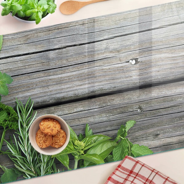 Glas-Schneidebrett mit Motiv grüner Kräuter auf Holzuntergrund