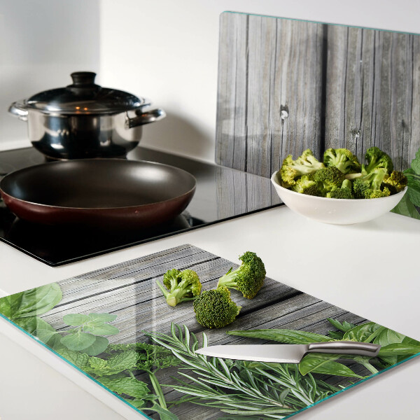 Glas-Schneidebrett mit Motiv grüner Kräuter auf Holzuntergrund