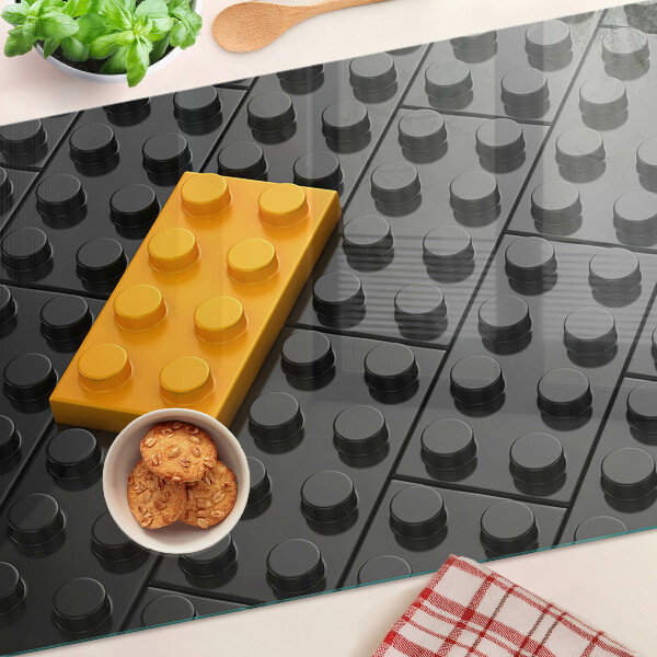 Glas-Schneidebrett mit Motiv aus LEGO-Steinen auf schwarzem Hintergrund