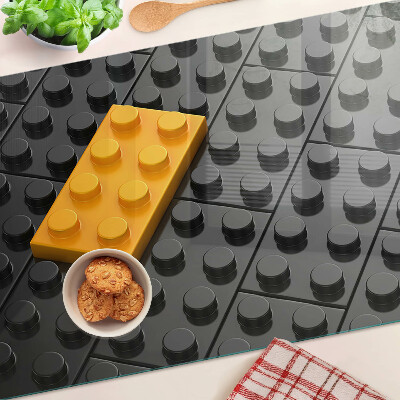 Glas-Schneidebrett mit Motiv aus LEGO-Steinen auf schwarzem Hintergrund