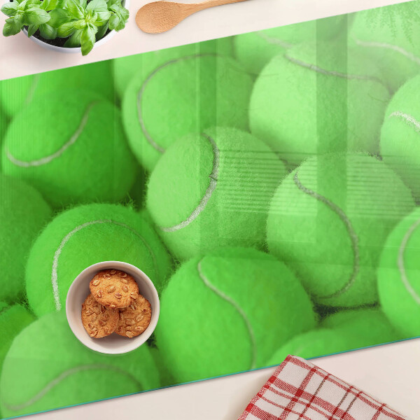 Schneidebrett mit Motiv von Tennisbällen auf grünem Hintergrund