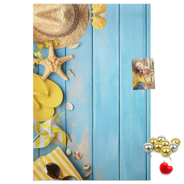 Pinnwand mit Sommeraccessoires vor blauem Holzgrund