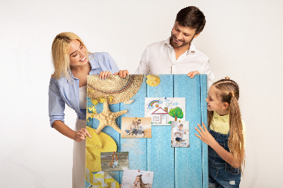 Pinnwand mit Sommeraccessoires vor blauem Holzgrund