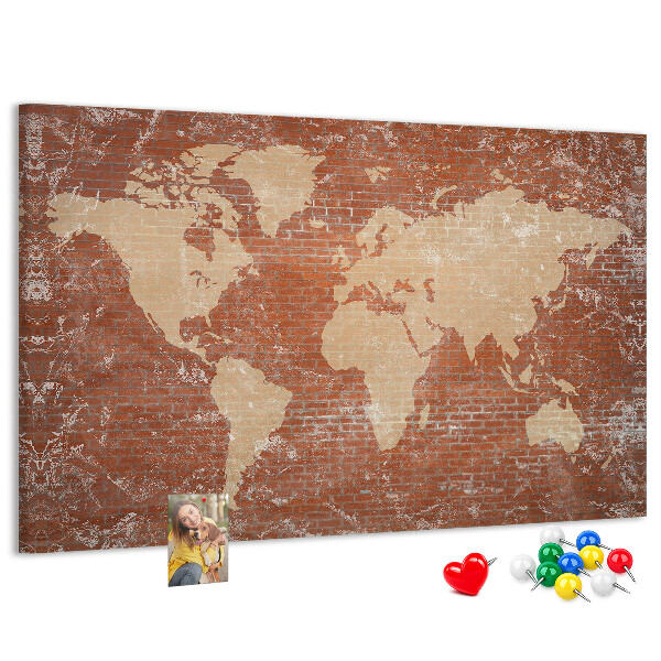 Korktafel mit Weltkartenmotiv vor einer Backsteinmauer