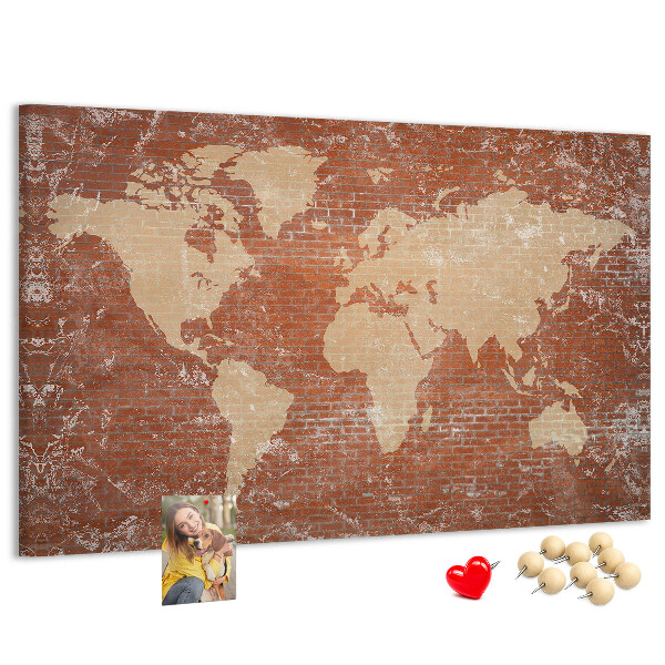 Korktafel mit Weltkartenmotiv vor einer Backsteinmauer