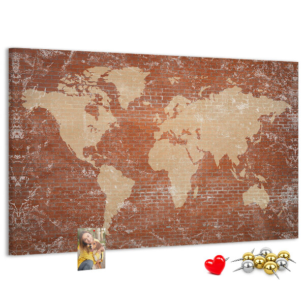 Korktafel mit Weltkartenmotiv vor einer Backsteinmauer
