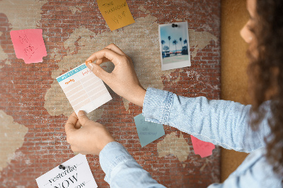 Korktafel mit Weltkartenmotiv vor einer Backsteinmauer