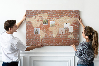 Korktafel mit Weltkartenmotiv vor einer Backsteinmauer