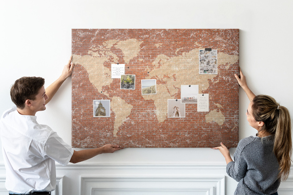 Korktafel mit Weltkartenmotiv vor einer Backsteinmauer