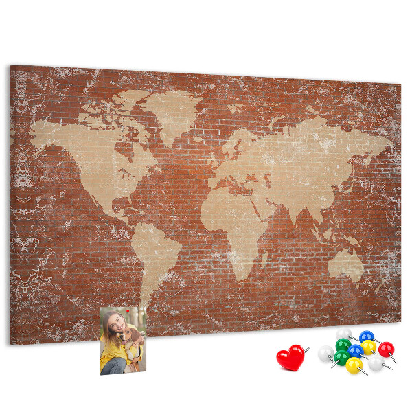 Korktafel mit Weltkartenmotiv vor einer Backsteinmauer