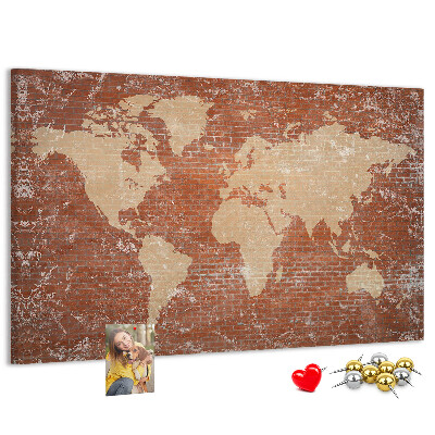 Korktafel mit Weltkartenmotiv vor einer Backsteinmauer