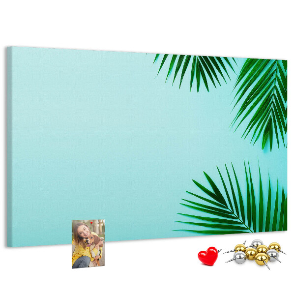 Kork-Pinnwand mit tropischen Blättern auf blauem Hintergrund