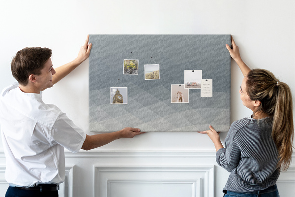Korktafel mit geometrischen Graustufendreiecken im Hintergrund