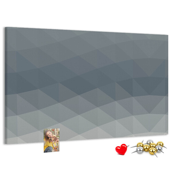 Korktafel mit geometrischen Graustufendreiecken im Hintergrund