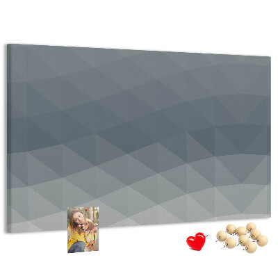 Korktafel mit geometrischen Graustufendreiecken im Hintergrund