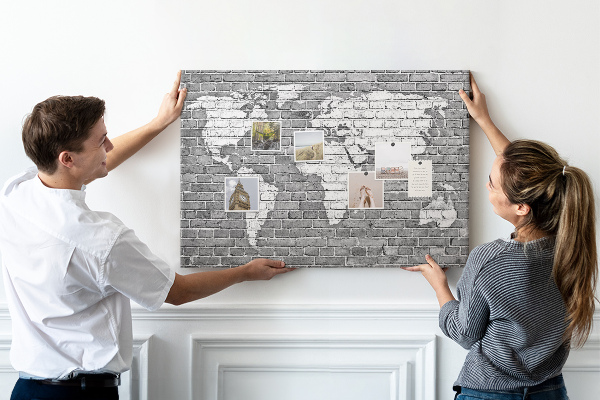 Korktafel mit Motiv Weltkarte an einer Backsteinmauer