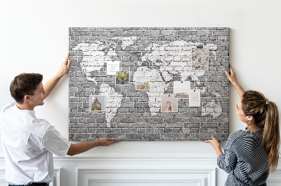 Korktafel mit Motiv Weltkarte an einer Backsteinmauer