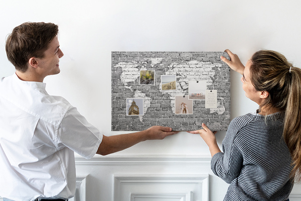 Korktafel mit Motiv Weltkarte an einer Backsteinmauer