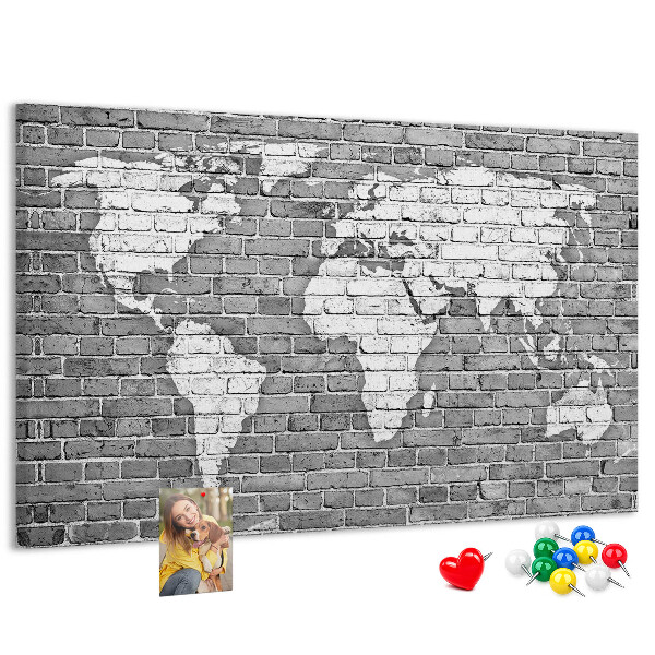 Korktafel mit Motiv Weltkarte an einer Backsteinmauer