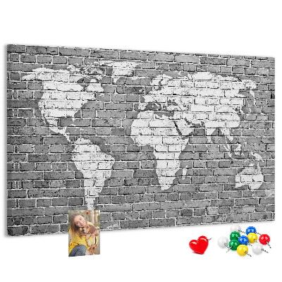 Korktafel mit Motiv Weltkarte an einer Backsteinmauer