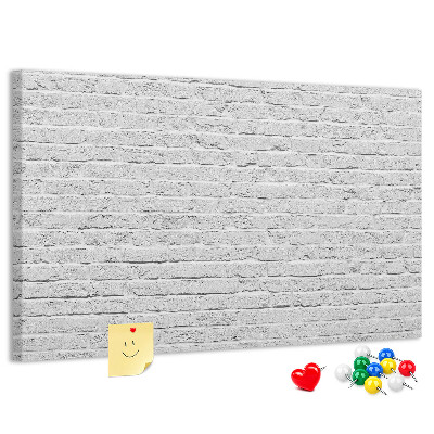 Korktafel mit weißem Backsteinmauer-Motiv und bunten Reißzwecken