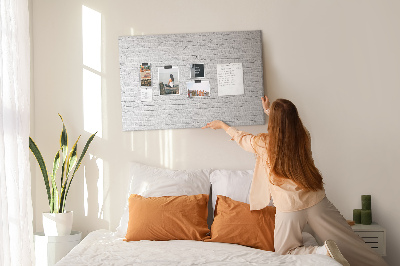 Korktafel mit weißem Backsteinmauer-Motiv und bunten Reißzwecken