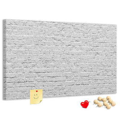 Korktafel mit weißem Backsteinmauer-Motiv und bunten Reißzwecken