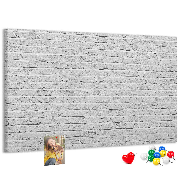 Korktafel mit weißem Backsteinmauer-Motiv und bunten Reißzwecken