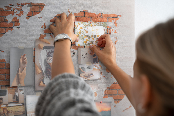 Kork-Pinnwand mit Motiv einer Weltkarte vor einer Backsteinmauer