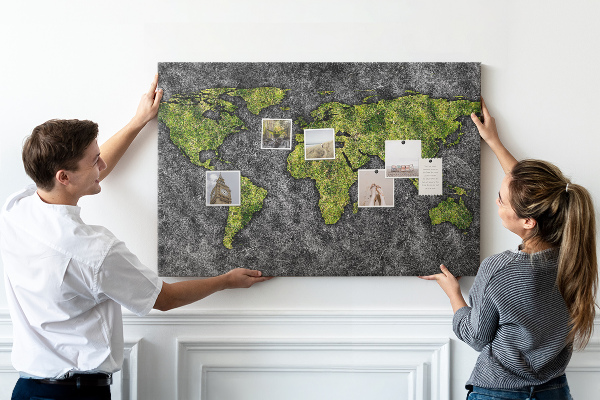Korktafel mit grüner Weltkarte auf grauem Hintergrund